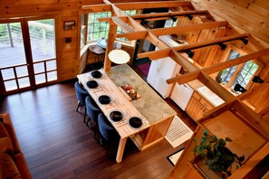 Ein Holzblockhaus-Interieur mit Essbereich, Küche und großen Fenstern.