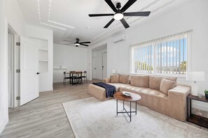 Ein modernes Wohnzimmer mit einer Couch, einem Couchtisch und Deckenventilatoren.
