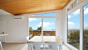 Ein moderner Essbereich mit Holzbalkendecke, großen Fenstern und Blick auf Grünflächen.