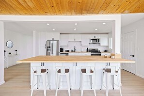 Eine moderne Küche mit weißen Schränken, einer Holztischinsel und Barhocker.