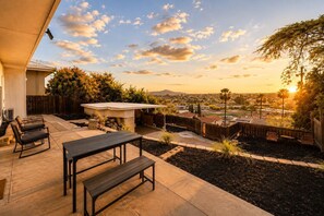 Eine Terrasse mit Tisch und Stühlen, ein überdachter Sitzbereich und Blick auf eine Wohngegend.