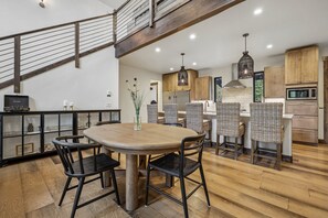 Eine moderne Küche mit Holzschränken, einem Esstisch mit Stühlen und einer Treppe.