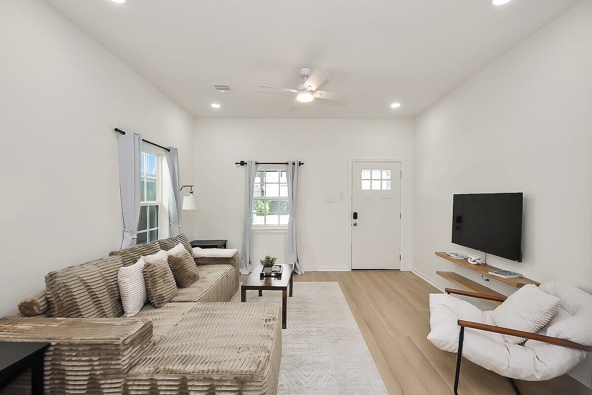 A modern living room with a sofa, a coffee table, a TV, and a ceiling fan.