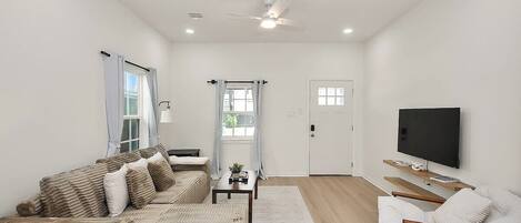 A modern living room with a sofa, a coffee table, a TV, and a ceiling fan.