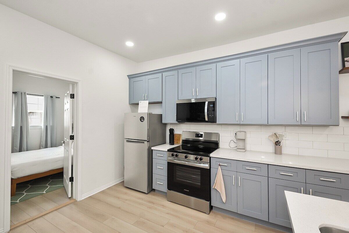 A compact kitchen with grey cabinets, a stainless steel stove, and a microwave.