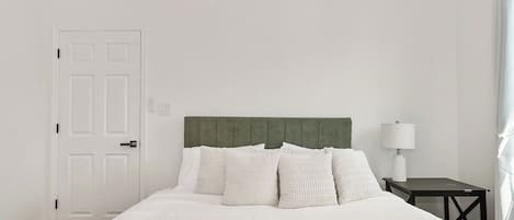 Une chambre d’hôtel avec un lit, une table de chevet, une lampe et une porte.