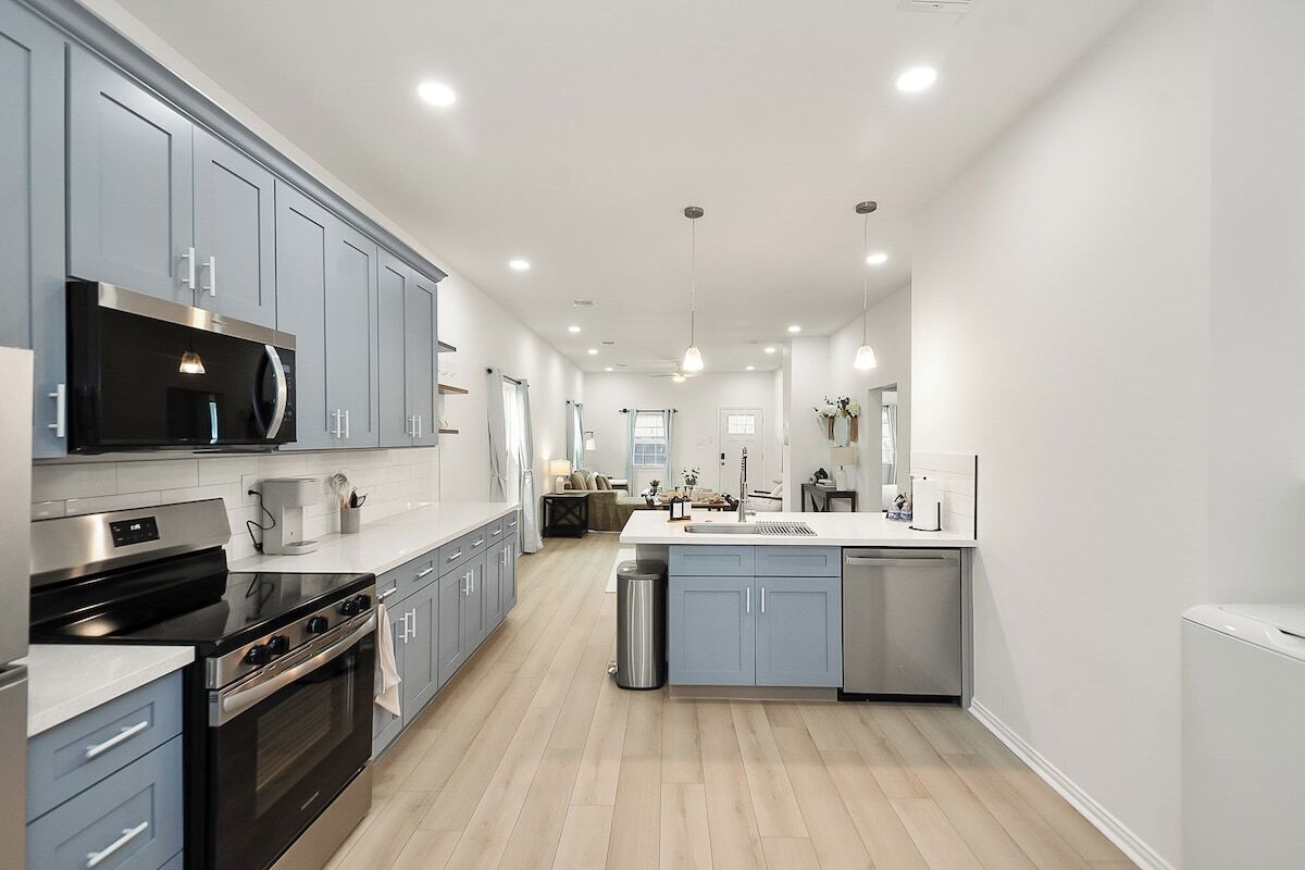 A modern kitchen with grey cabinets, stainless steel appliances, and a central island.