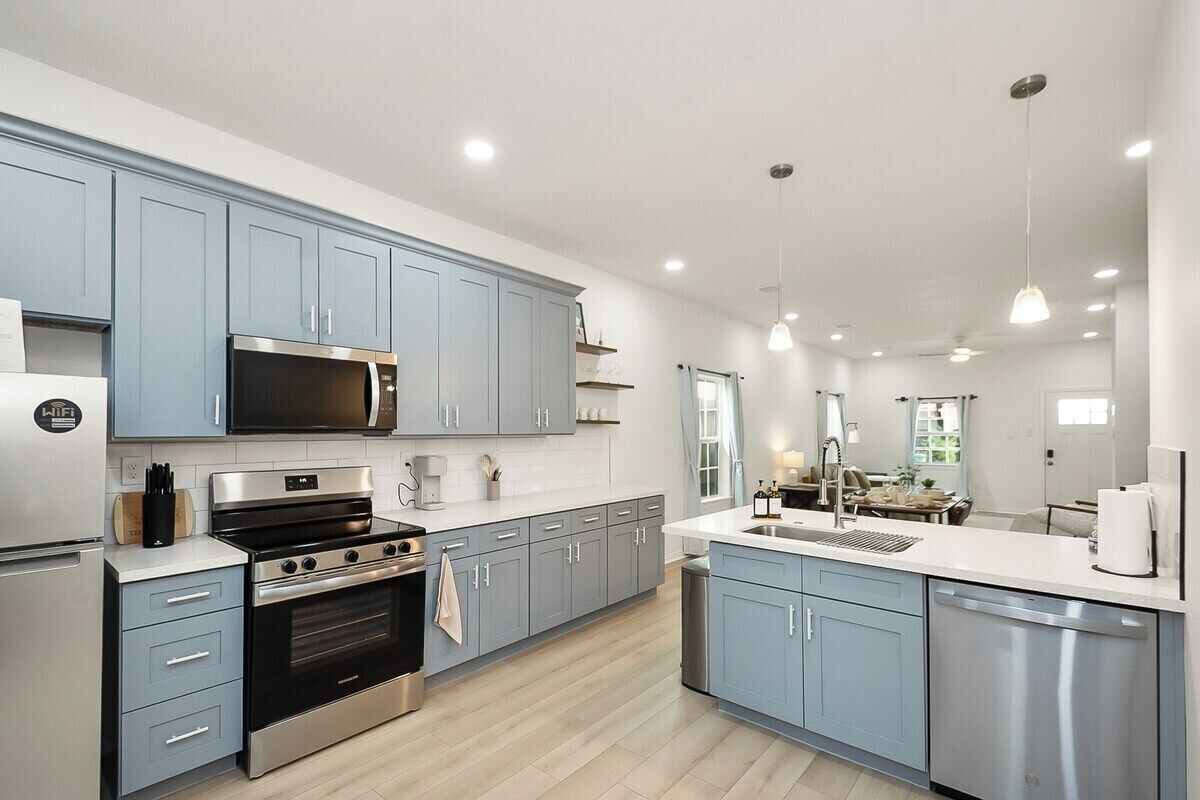 A modern kitchen with grey cabinets, stainless steel appliances, and a central island.