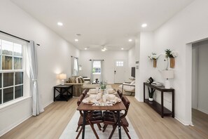 A spacious dining area with a wooden table set for four, a sofa, and a small side table with a lamp. - Perfect 3-bedroom house in peaceful Houston neighborhood (Houston)