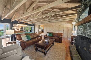 Ein geräumiges Wohnzimmer mit Holzbalken, Ledersofas, einem Billardtisch und einem Kamin.