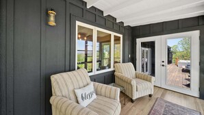 A room with two striped armchairs, a bench, a door leading to an outdoor area, and a wall-mounted light fixture. - Sunrise Mountain Views, Hot Tub, Fire Pit & Spacious Retreat Near Downtown Boone (Boone)