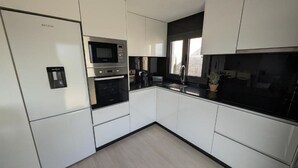 Een moderne keuken met witte kasten, een ingebouwde oven, magnetron en een zwart aanrecht.