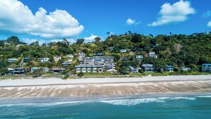 A coastal hotel with multiple buildings, beachfront access, and lush greenery. - Vista On The Beach at The Sands (Waiheke Island)
