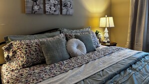 A bedroom with a bed, pillows, a nightstand, a lamp, and wall art. - 2-bedroom 2-bath condo in lovely Mishawaka close to Notre Dame. (Mishawaka)