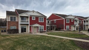 A row of two-story townhouses with a front porch, a garage, and a small front yard. - 2-bedroom 2-bath condo in lovely Mishawaka close to Notre Dame. (Mishawaka)