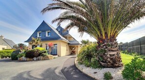 A house with a triangular roof, a palm tree, and a well-maintained garden. - Ty Royau'M-Maison - TREVOU TREGUIGNEC (TREVOU TREGUIGNEC)