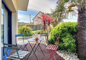An outdoor patio with a table and chairs, surrounded by greenery and a house in the background. - Ty Royau'M-Maison - TREVOU TREGUIGNEC (TREVOU TREGUIGNEC)