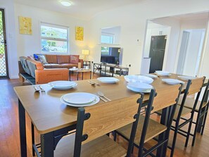 Un comedor con una mesa de madera dispuesta para cuatro personas, rodeada de sillas.