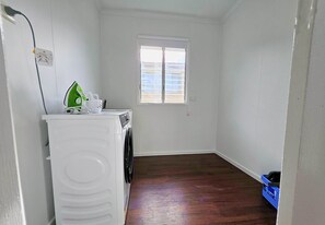 Un cuarto de lavandería con lavadora, tendedero y ventana.