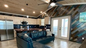Eine moderne Küche mit Edelstahlgeräten, ein Essbereich mit einem dunkelblauen Sofa und einer Wand mit Fischgrätmuster.