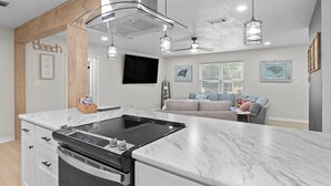 Una cucina moderna con un'isola grande, forno integrato e luci a sospensione.