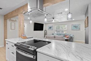 A modern kitchen with a large island, built-in oven, and pendant lighting. - Sleeps Ten, Pet friendly, White sand beaches (Pensacola)