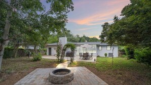 Una casa moderna con un patio, una chimenea y una zona de estar cubierta al aire libre.