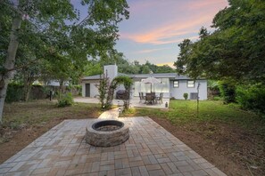 A modern house with a patio, a fire pit, and a covered outdoor seating area. - Sea`s the Day Getaway (Pensacola)