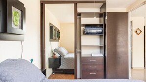 Un dormitorio con cama, mesita de noche, armario y espejo.