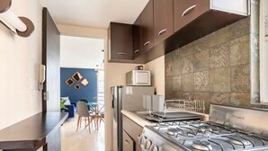 Una cocina moderna con electrodomésticos de acero inoxidable, un comedor con pared azul y techo blanco, y un salpicadero de azulejos estampados.