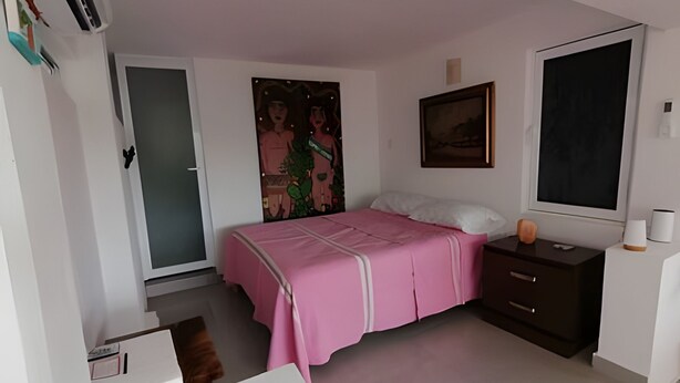 A bedroom with a bed, a dresser, a door, a painting, and a window. - Pinky Playa Salchi Valentina (San Pedro Pochutla)