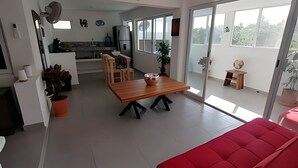 A modern living space with a dining area, kitchen, and a red sofa. - Pinky Playa Salchi Valentina (San Pedro Pochutla)
