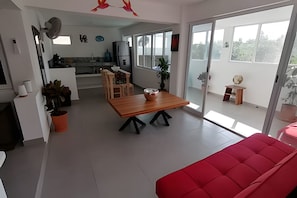 A modern living space with a dining area, kitchen, and a red sofa. - Pinky Playa Salchi Valentina (San Pedro Pochutla)