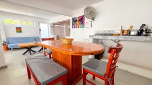 A modern kitchen with a wooden dining table, chairs, and a built-in stove. - Pinky Playa Salchi Valentina (San Pedro Pochutla)