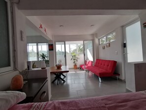 Una sala de estar moderna con un sofá rojo, una mesa de comedor y un ventanal grande.