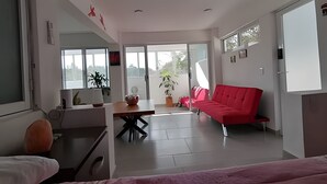 A modern living room with a red sofa, a dining table, and a large window. - Pinky Playa Salchi Valentina (San Pedro Pochutla)