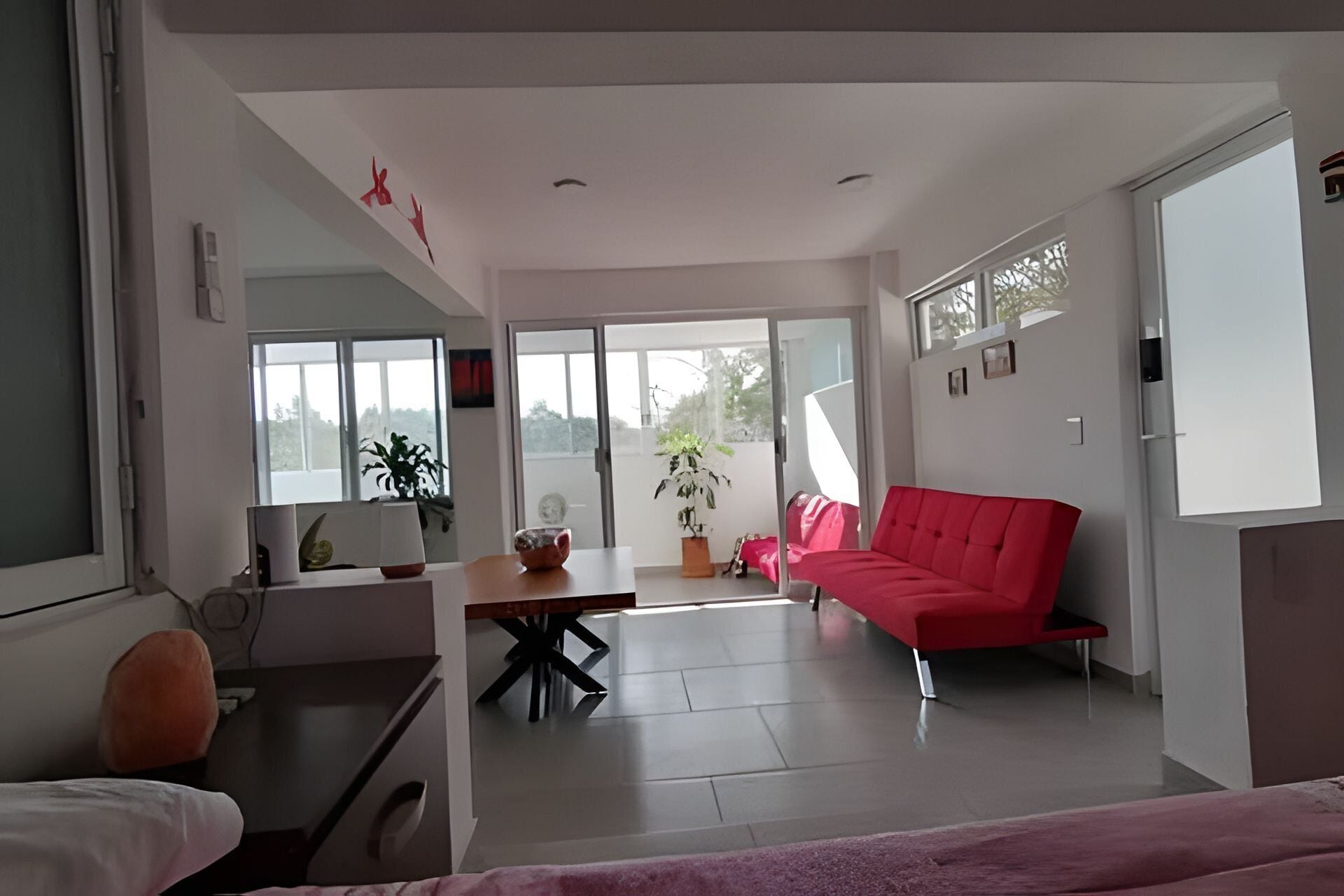A modern living room with a red sofa, a dining table, and a large window.