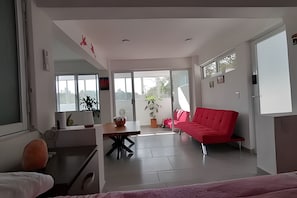 Un salón moderno con un sofá rojo, una mesa de comedor y un ventanal grande.