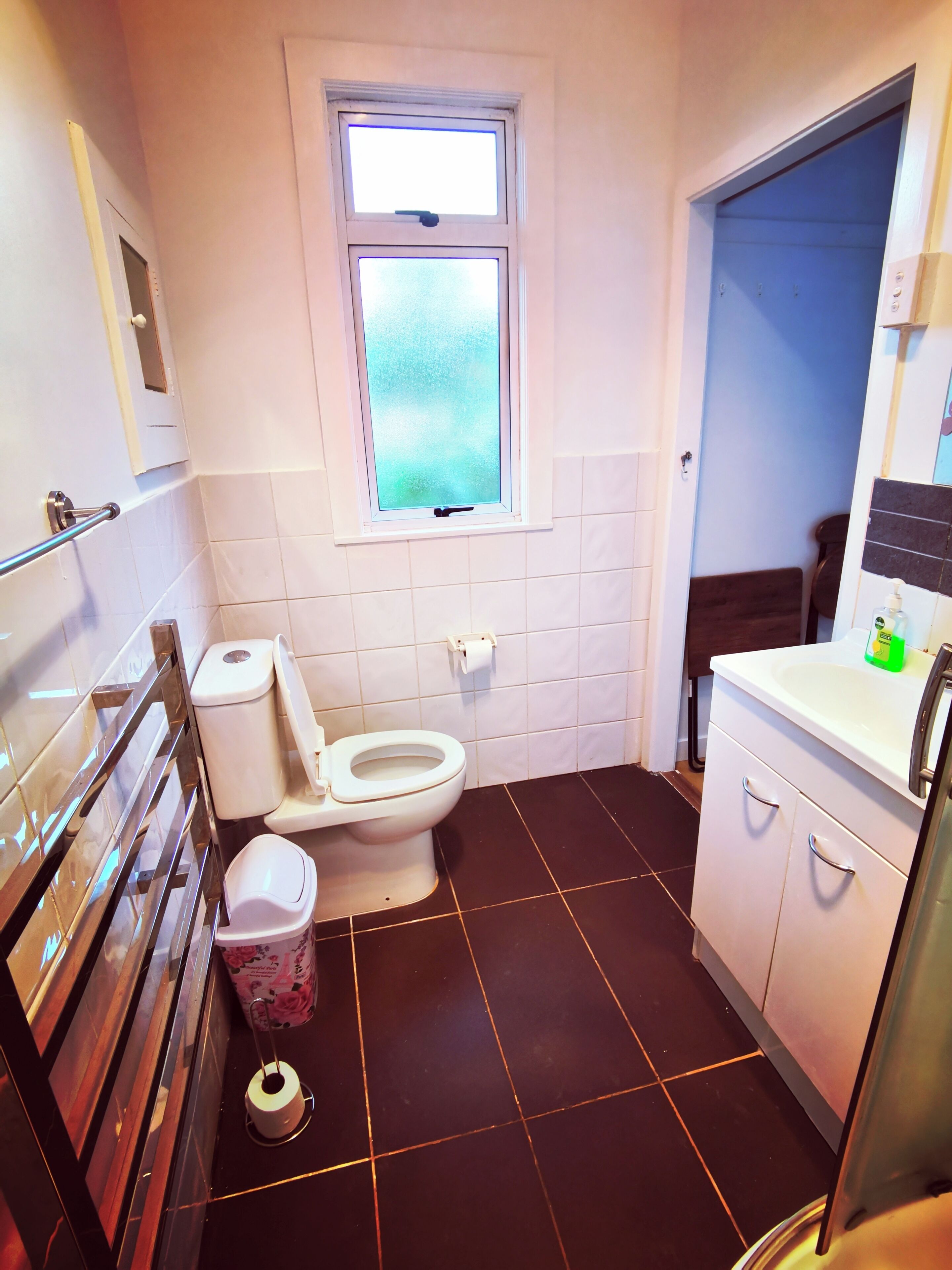 Une salle de bain avec des toilettes, une fenêtre, un lavabo et un miroir.