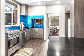 Een moderne keuken met een gasfornuis, oven en blauwe kastjes.