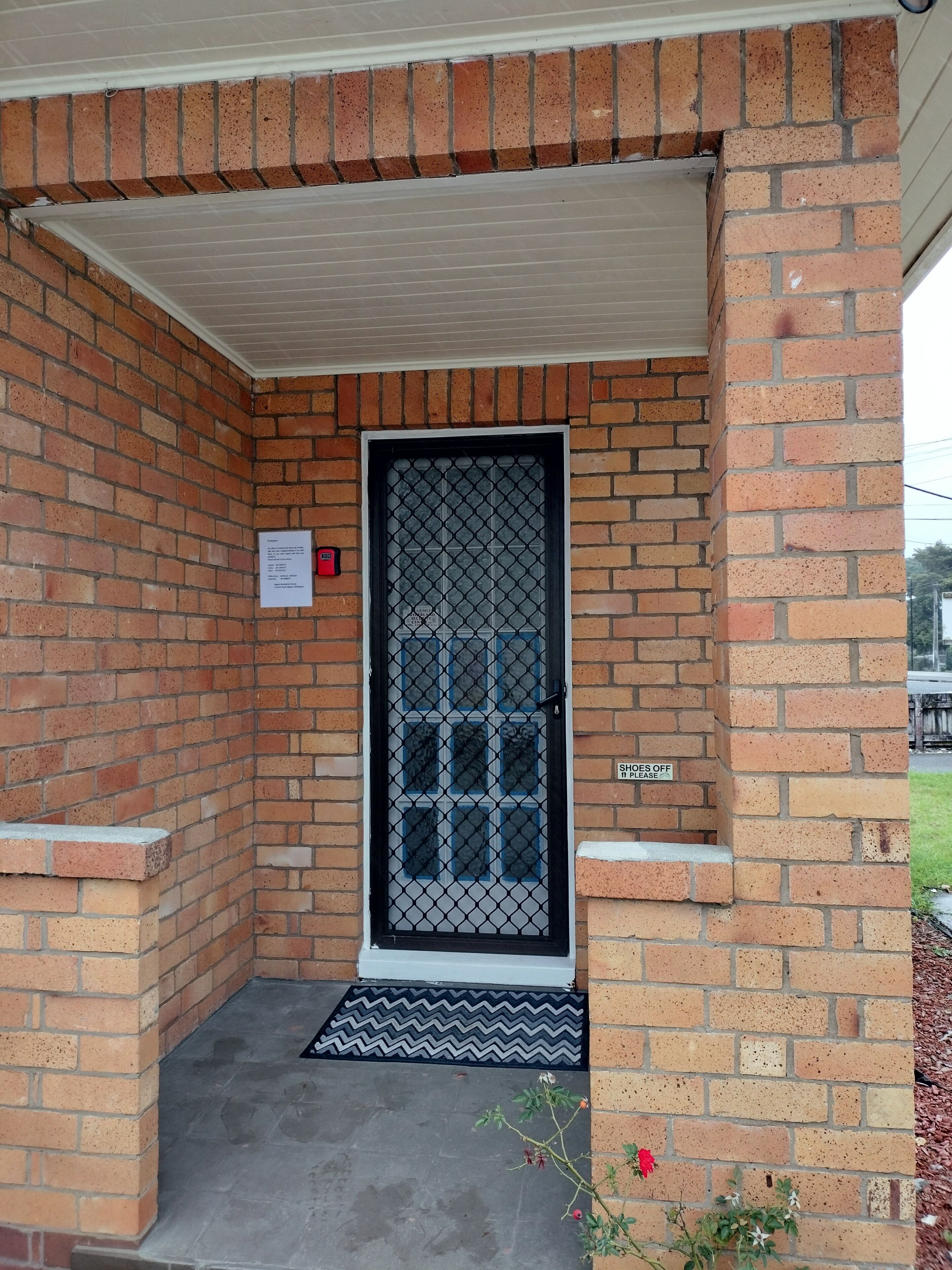 A brick exterior with a metal gate, a doormat, and a sign indicating the door is for lease.
