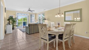 A dining area with a round table, chairs, a ceiling fan, and a large window. - 6 Sunset Island Drive 3F (Ocean City)