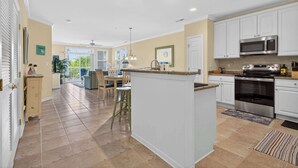 A spacious kitchen with white cabinets, a central island, and a dining area with chairs and a table. - 6 Sunset Island Drive 3F (Ocean City)