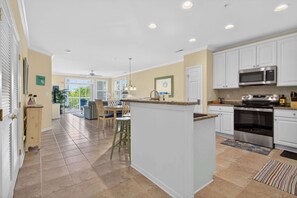 A spacious kitchen with white cabinets, a central island, and a dining area with chairs and a table. - 6 Sunset Island Drive 3F (Ocean City)
