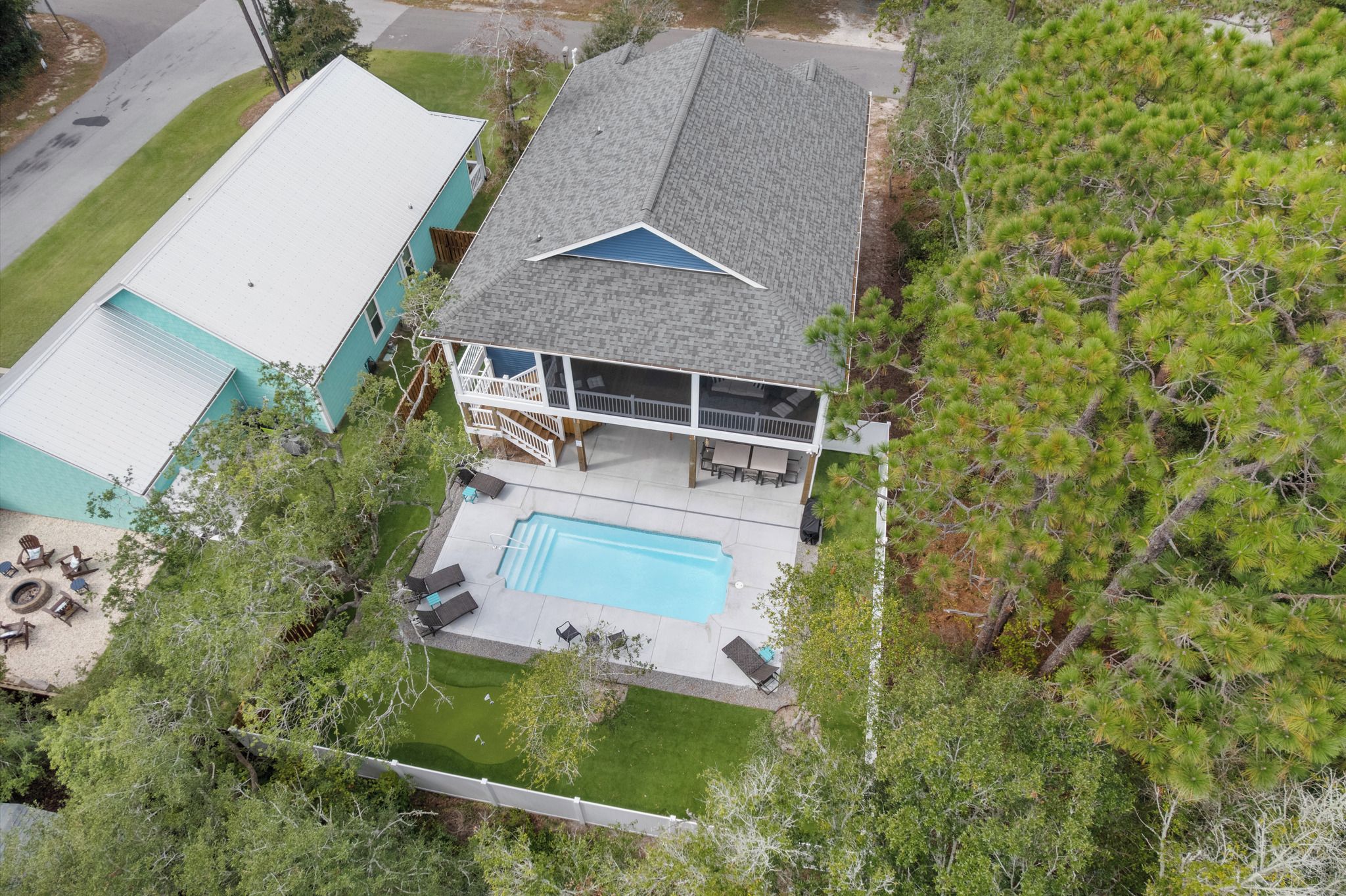 A two-story house with a swimming pool, a covered patio, and a fenced yard.
