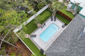 A rectangular swimming pool with a surrounding deck, a small putting green, and a tree. - Saltwater Pool/Putting Green + Minutes to Beach (Oak Island)