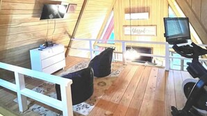 Une pièce aux murs en bois, avec un ventilateur de plafond, une télévision, un bureau et un ordinateur.