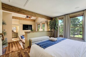 Une chambre à coucher avec un lit, un banc, une télévision et un ventilateur de plafond.
