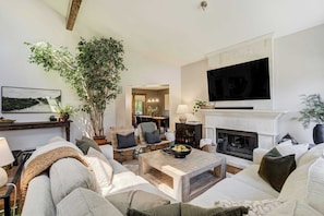 A living room with a fireplace, television, and comfortable seating. - Fossil Run! Curated Home w/ Wellness & Game Room (Colorado Springs)