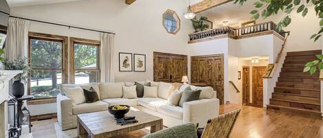 A spacious living room with a large sofa, wooden coffee table, and a staircase leading to an upper level.